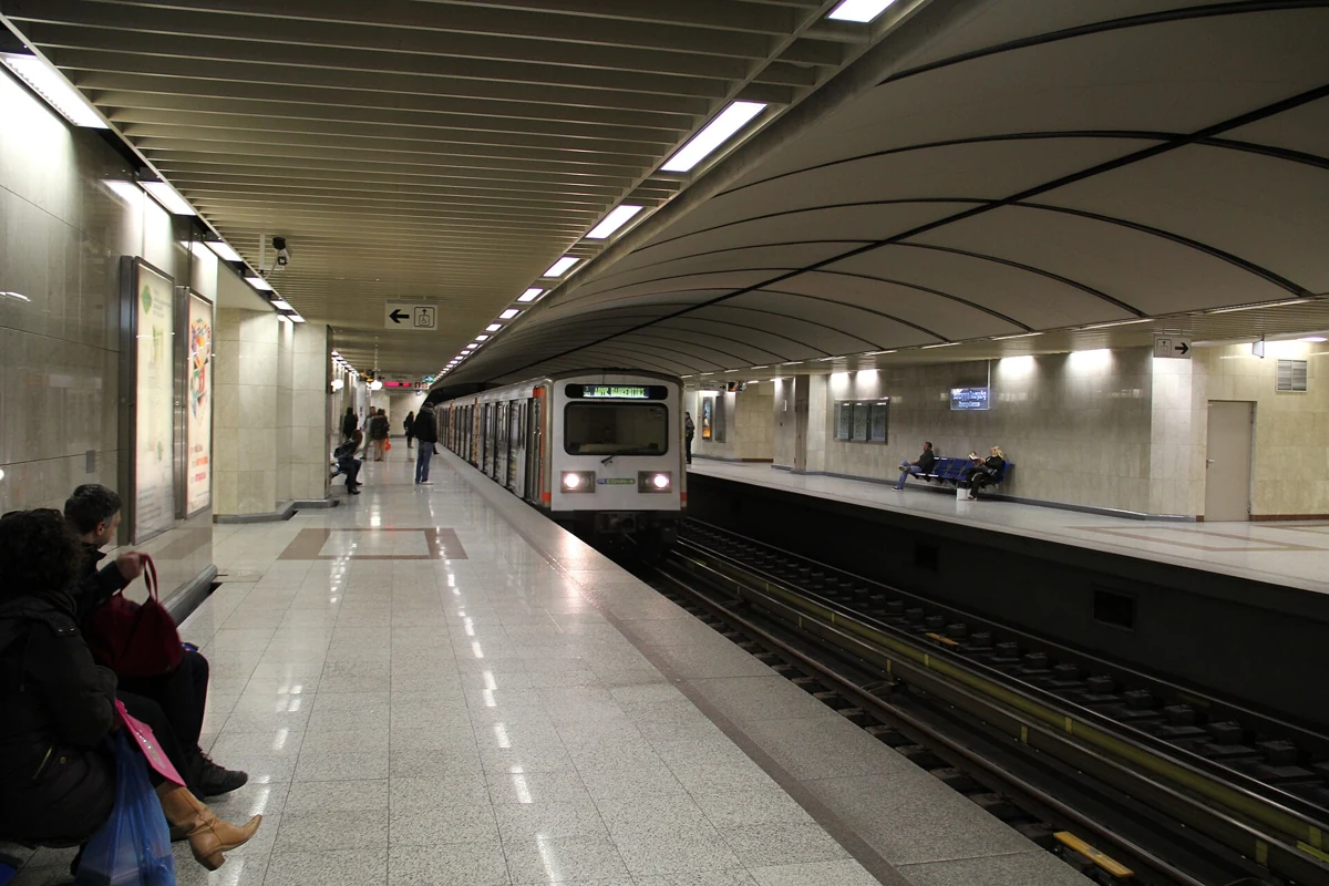A train arriving at an Athens metro platform with passengers waiting on the marble, Greece