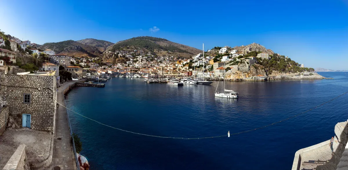 Stone captains' houses rising around the horseshoe harbour of Hydra, a day trip from Athens, Greece