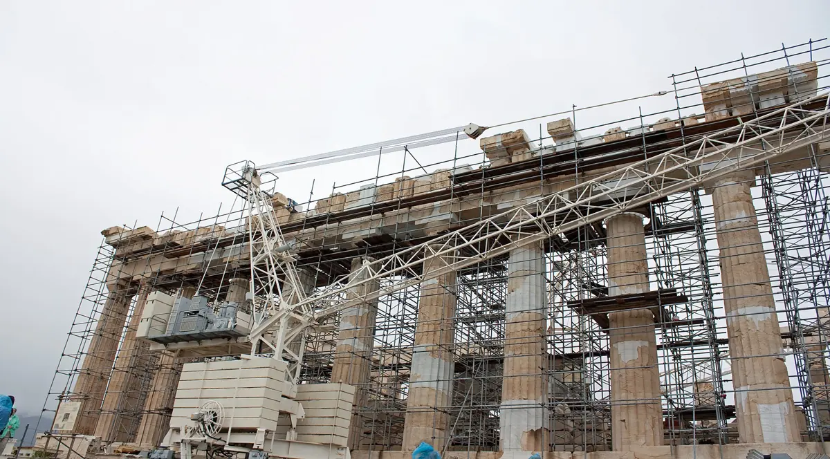 A crane and scaffolding across the flank of the Parthenon during the restoration, with new marble fills visible on the column drums, Acropolis of Athens, Greece